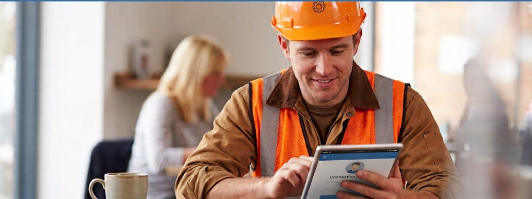 Contractor in a hard hat reviewing funding options on a tablet